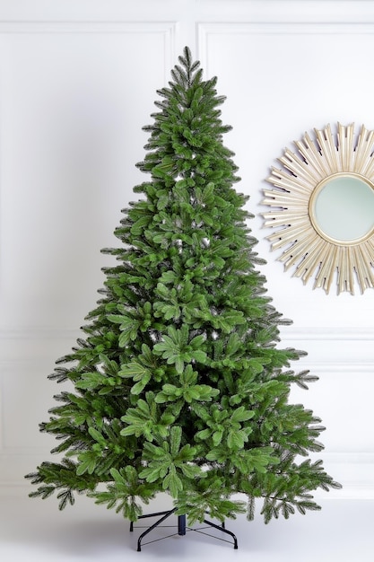 Artificial Christmas green tree without decorations on a metal stand isolated on a white background