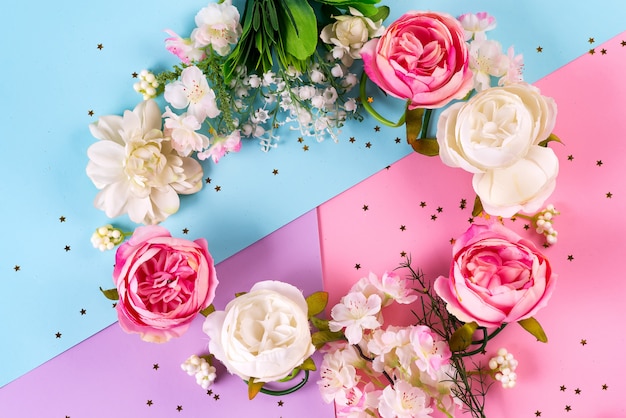 Artificial flowers on three color paper background. Floral wreath with golden stars