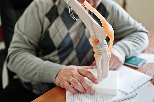 Photo artificial human knee joint model in medical office on table.