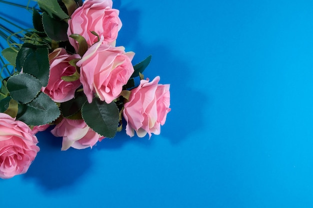 Artificial pink roses on a blue background.