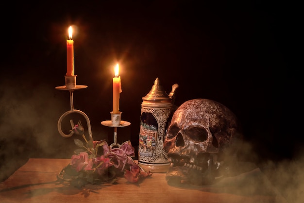 Artificial skull and Candlestick on wooden layer on black background