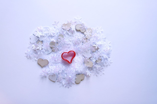 Artificial snowflakes and red decorative heart on white soft background.