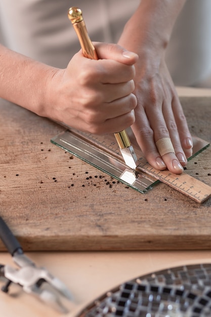 Artist cutting sheets of stained glass into small mosaic squares. Close-up