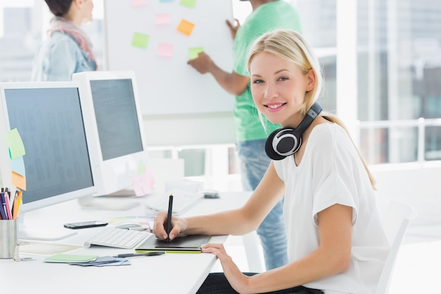 Artist drawing something on graphic tablet with colleagues behind