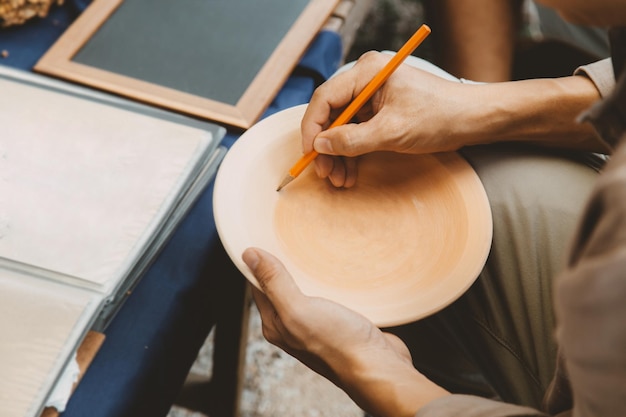 Artist paint sketch drawing Sukhothai traditional style pattern on dish earthenware making of handcraft pottery in Sukhothai Thailand