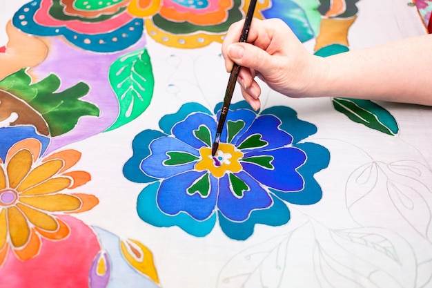 Artist paints flower in batik on silk canvas