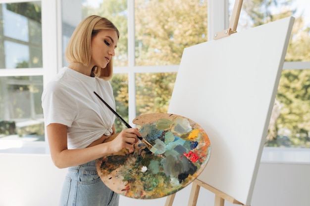 The artist paints in the studio Attractive girl wearing a white Tshirt