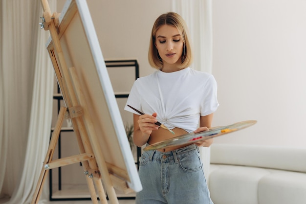 The artist paints in the studio Attractive girl wearing a white Tshirt