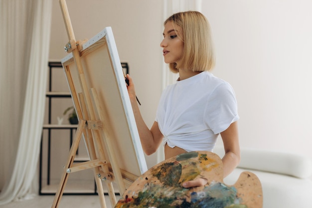 The artist paints in the studio Attractive girl wearing a white Tshirt