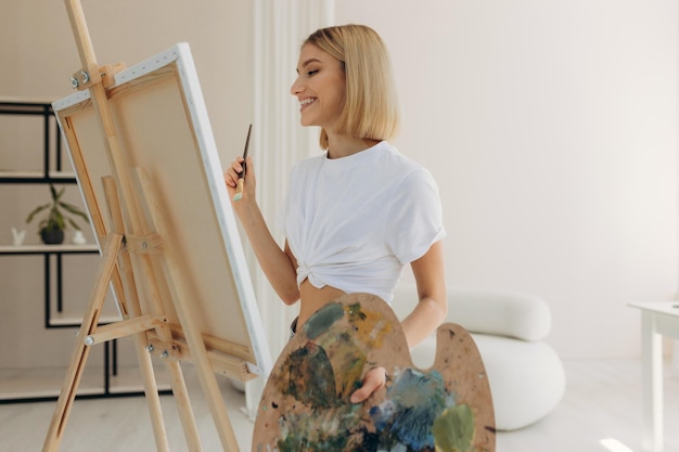 The artist paints in the studio Attractive girl wearing a white Tshirt