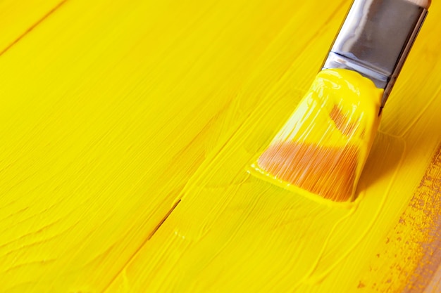 An artist paints wooden boards with a brush of acrylic yellow paint