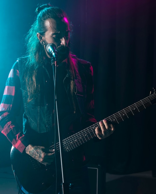 Photo artist playing guitar and having a microphone