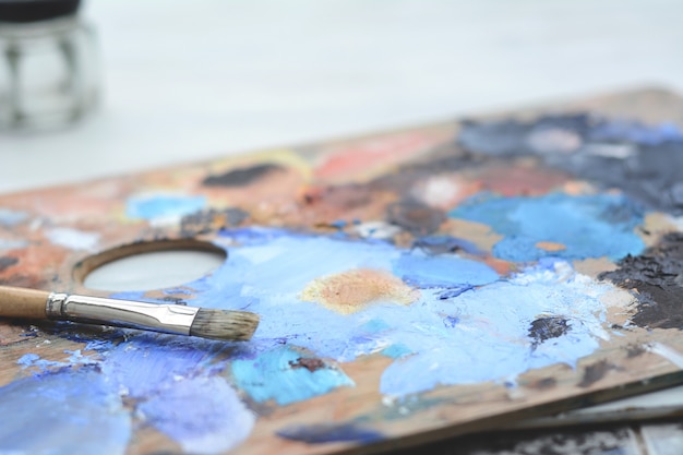 Artist's palette with colorful oil paint strokes and paintbrushes 