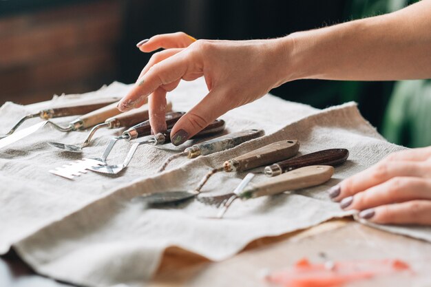 Artist supplies. Art craft set composition arranged on ivory textile. Woman hand choosing tool.