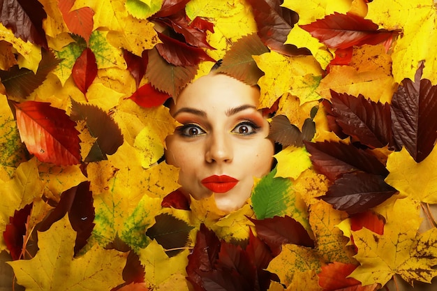 Artistic conceptual autumn girl portrait Colorful leaves Leaves of trees around an emotional face Autumn is coming