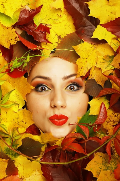 Artistic conceptual autumn girl portrait Colorful leaves Leaves of trees around an emotional face Autumn is coming