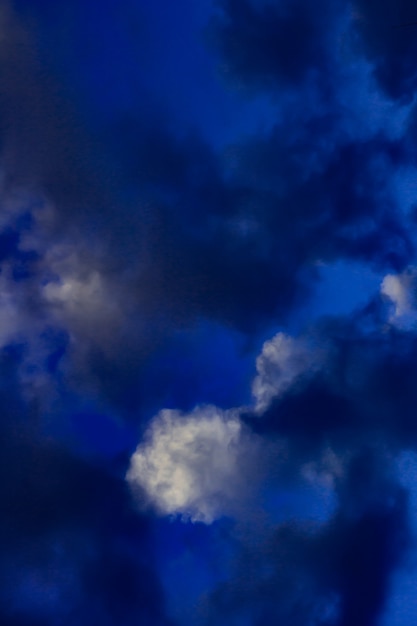 Artistic photo of sky with clouds in dark blue and white colors, abstract nature background design