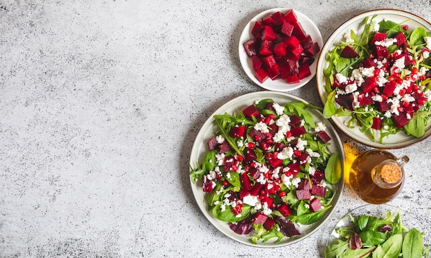 Arugula Beet and cheese salad with pomegranate and dressing on plate on grey stone kitchen table background place for text top view