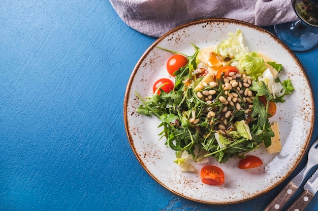 Arugula healthy salad with pine nuts tomatoes and cheese Top view Copy space