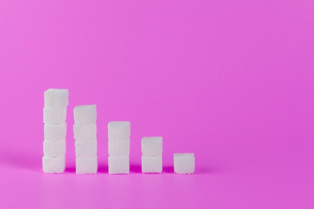 Ascending stacks of sugar cubes on pink