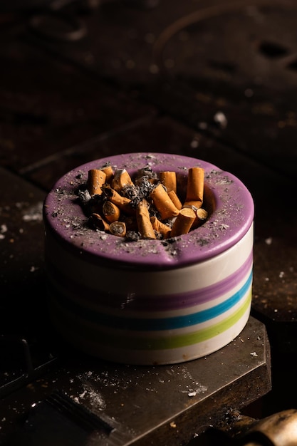 Ashtray with many cigarette butts on a dark background