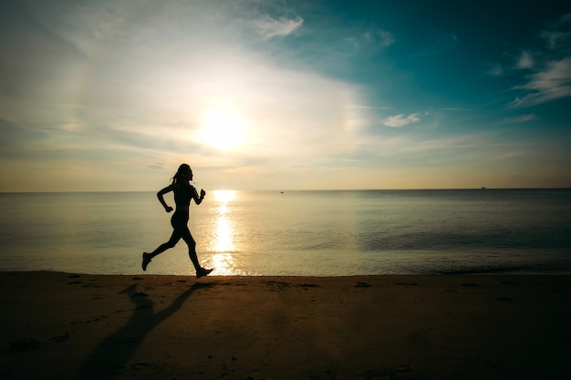 Asia beautiful woman in sport ware ready to  exercising by running on the beach. silhouette style.