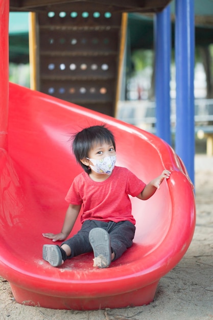 Asia child smiling playing on slider bar toy outdoor playground happy preschool little kid having funny while playing on the playground equipment in the daytime in summer