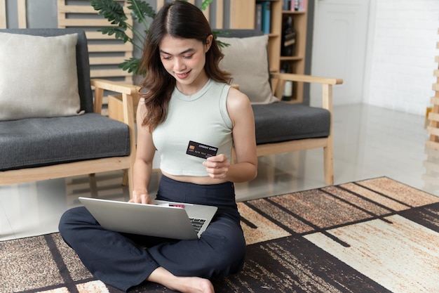 Asia girl holding in hands demonstrating bank card at home