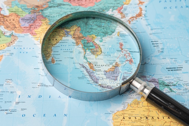 Asia, Magnifying glass close up with colorful world map.