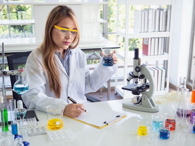 Asia scientific researcher holding a test tube of clear solution in a lab