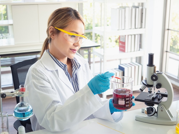 Asia scientific researcher holding a test tube of clear solution in a lab