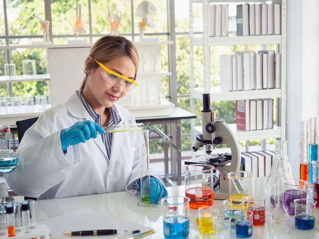 Asia scientific researcher holding a test tube of clear solution in a lab