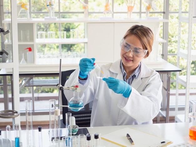 Asia scientific researcher holding a test tube of clear solution in a lab