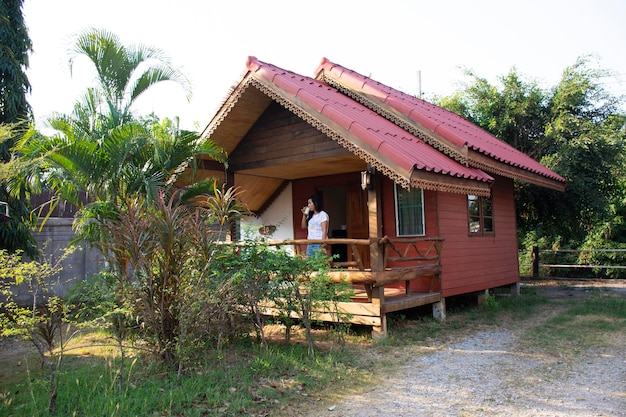 Asia thai woman drinking soy milk on patio of wooden hut of resort and homestay in morning time at the City of Phraya Lae the Brave in Chaiyaphum Thailand