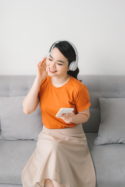 Asia woman listening music in earphones on sofa