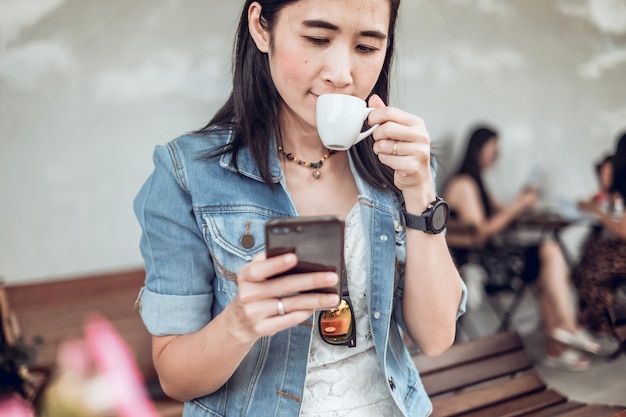 Asia woman sitting in the coffee shop and using mobile phone