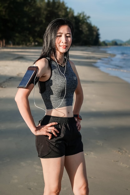 Asia woman in sport ware exercising and running on the beach.