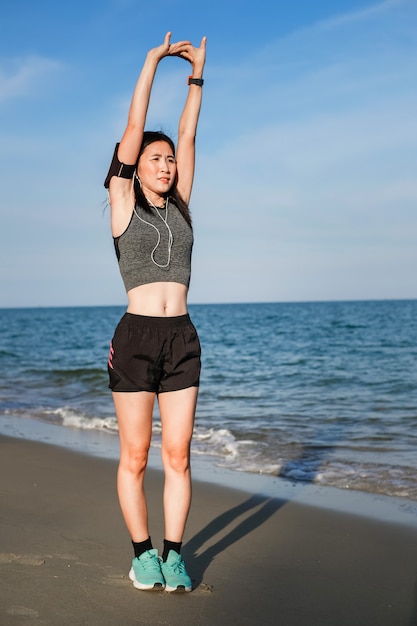 Asia woman in sport ware exercising and running on the beach.