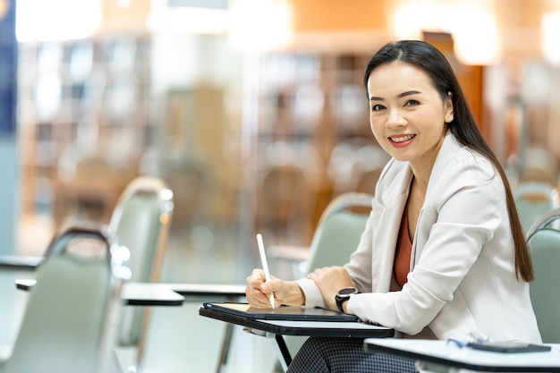 Asia woman Teacher taking notes from tablet at library at university