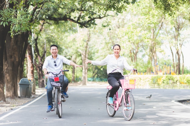 Asian Asian couples are riding bicycles in the garden happily and having fun on the weekends.