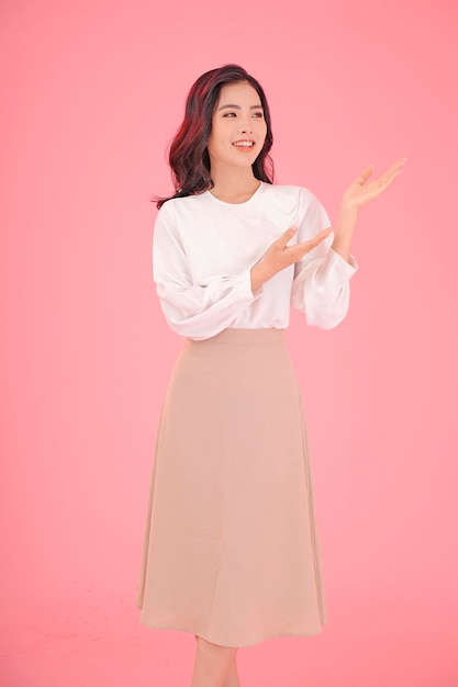 Asian attractive beautiful young woman with hand gesture showing with finger on the copy space isolated on background