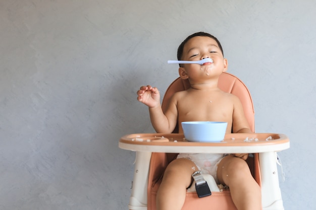 Asian baby boy eating food by himself