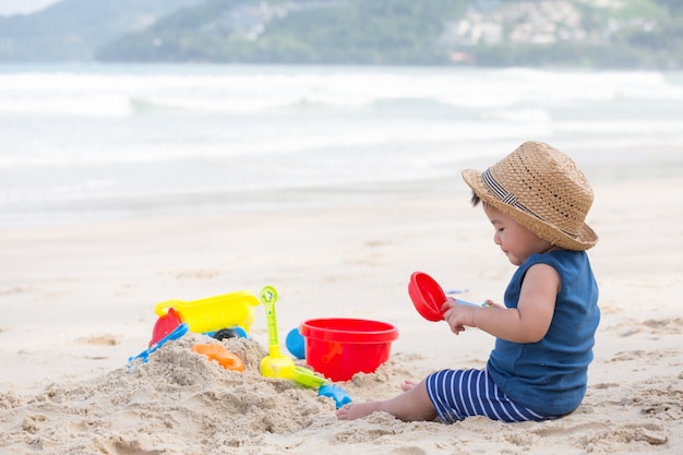 Asian baby boy playing sand on the beach