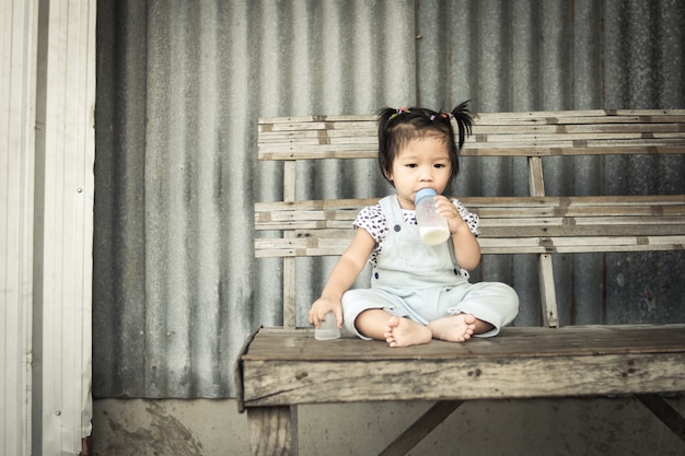 Asian baby girl with bottle of milk sitting alone on table