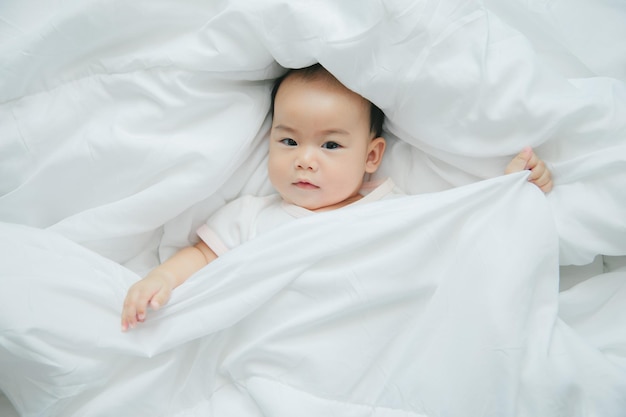 Asian baby lying on bed with soft blanket indoors cute little asian newborn baby