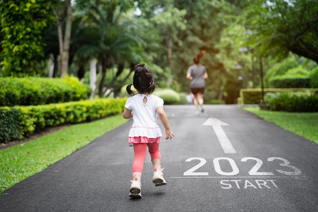 Asian baby running start into the new year 2023 Start up of runner woman running on nature race track go to Goal of Success People running as part of Number 2023 Sport health care