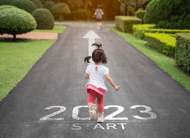 Asian baby running start into the new year 2023 Start up of runner woman running on nature race track go to Goal of Success People running as part of Number 2023 Sport health care