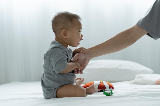 An Asian baby trusts his father's hand to stand up father and son spending time together