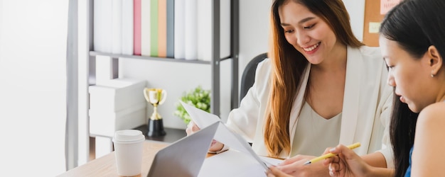 Asian beautiful empower woman smiling and talking with friend working at meeting room in office interior background with copy spaceOwner businesswoman startup with confident and cheerful