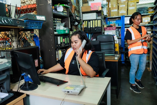 Asian beautiful fat woman warehouse worker talking by telephone customer order in desktop computer at office warehouse factory Plus size women inspecting products working